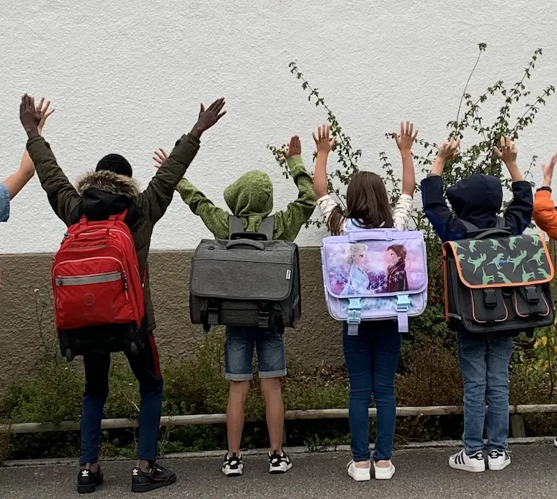 Des enfants des dos levant les bras